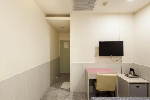a room with a desk and a tv on a wall at Ruei Gung Business Hotel Kaohsiung in Kaohsiung