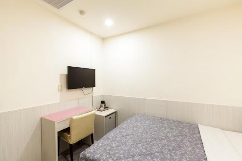 a room with a bed and a desk and a tv at Ruei Gung Business Hotel Kaohsiung in Kaohsiung