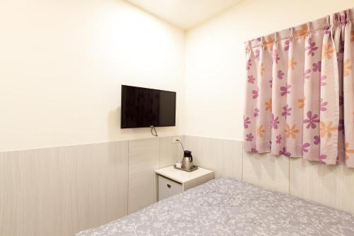 a bedroom with a bed and a flat screen tv at Ruei Gung Business Hotel Kaohsiung in Kaohsiung
