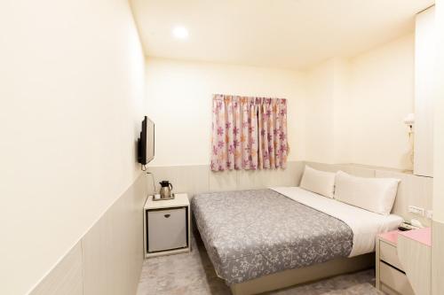 a small bedroom with a bed and a window at Ruei Gung Business Hotel Kaohsiung in Kaohsiung