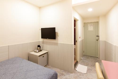 a bedroom with a bed and a tv on the wall at Ruei Gung Business Hotel Kaohsiung in Kaohsiung