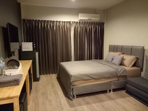 a bedroom with a bed and a couch and a window at My Home N1 - BTS Ratchathewi in Bangkok