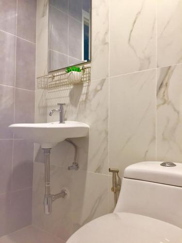 a white bathroom with a sink and a toilet at My Home N1 - BTS Ratchathewi in Bangkok