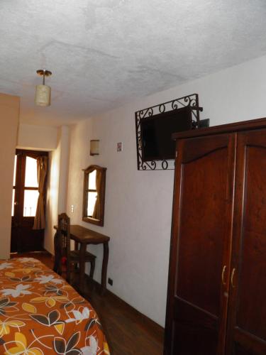 una camera da letto con un letto e una TV a parete di Hotel Barroco a Puebla