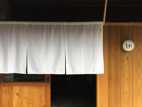 a window with a white curtain and a clock at the CUE in Tanabe