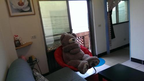 a teddy bear sitting on a red pillow in a room at Jiufen B&B Uncle Xie's in Jiufen