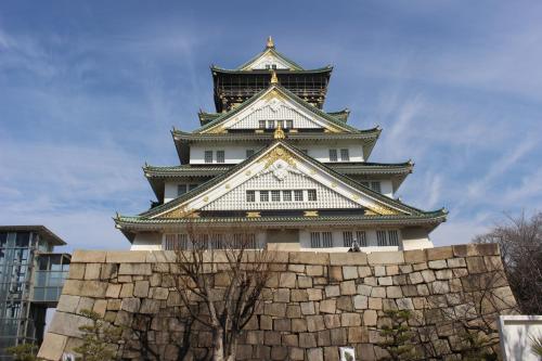 a tall tower with a stone wall in front of it at Hotel Sunplaza 2 Annex in Osaka