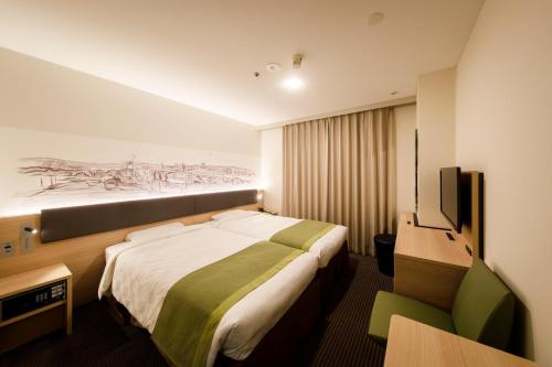 a hotel room with a bed and a television at Shin Osaka Esaka Tokyu REI Hotel in Suita