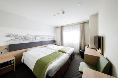 a hotel room with a bed and a flat screen tv at Shin Osaka Esaka Tokyu REI Hotel in Suita