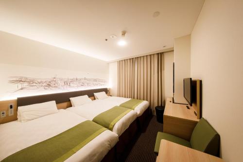 a hotel room with two beds and a television at Shin Osaka Esaka Tokyu REI Hotel in Suita