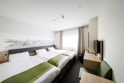 a hotel room with two beds and a television at Shin Osaka Esaka Tokyu REI Hotel in Suita