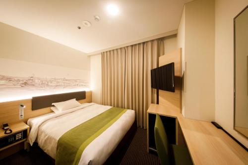 a hotel room with a bed and a tv at Shin Osaka Esaka Tokyu REI Hotel in Suita