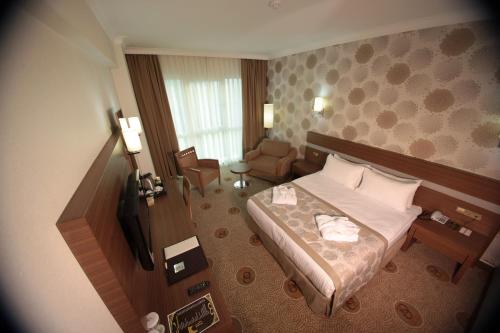 Habitación de hotel con cama y silla en Buyuk Osmaniye Hotel, en Osmaniye