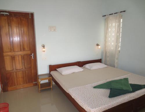 a bedroom with a bed and a wooden door at Sea Pearl Guesthouse in Candolim