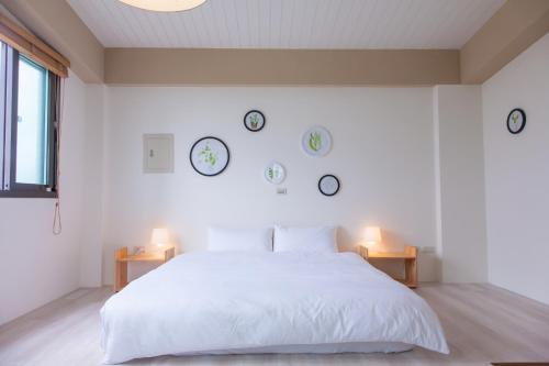 a bedroom with a white bed and clocks on the wall at Stay Homestay in Toucheng