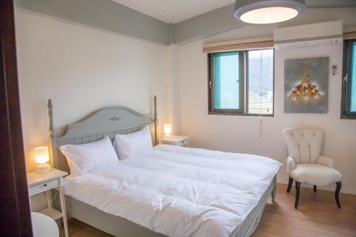 1 dormitorio con 1 cama blanca grande y 1 silla en Stay Homestay, en Toucheng