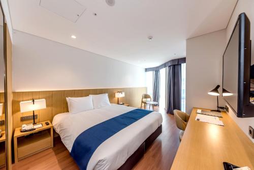 a hotel room with a bed and a television at Hotel Sirius in Jeju