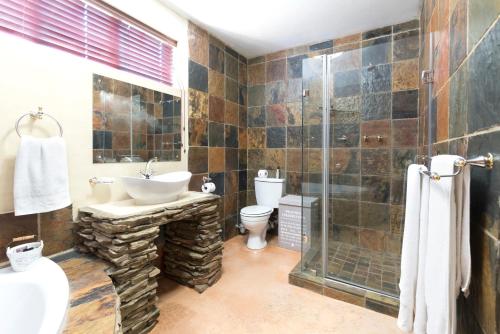 a bathroom with a toilet and a sink and a shower at Our Heritage Guesthouse in Kempton Park