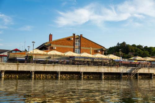 a bridge over the water with tables and umbrellas at Kafana Zlatna Ribica in Golubac