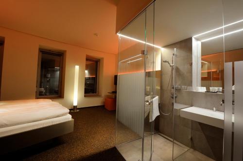a bathroom with a bed and a sink and a shower at Scala Turm Hotel Restaurant in Jena