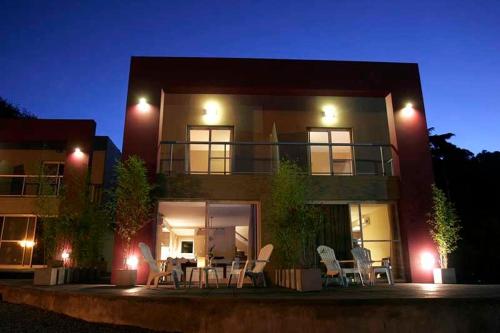 a building with tables and chairs in front of it at night at Hotel Sierra de los Padres in Sierra de los Padres