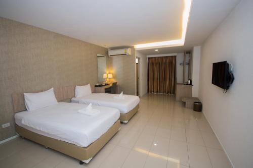 a hotel room with two beds and a television at Villa Baron SHA PLUS in Nonthaburi