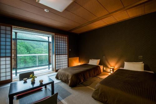 um quarto com 2 camas e uma grande janela em Takamiya Hotel Rurikura Resort em Zao Onsen