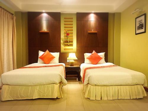 a hotel room with two beds with orange pillows at Hua Hin White Sand in Hua Hin