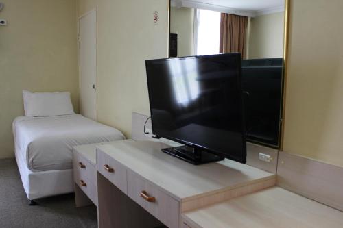 Zimmer mit einem TV auf einer Kommode mit einem Bett in der Unterkunft El Toro Motor Inn in Warwick Farm