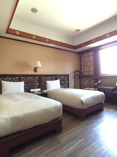 a bedroom with two beds and a window at Hua Du Hotel in Keelung