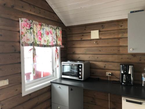 eine kleine Küche mit einer Mikrowelle und einem Fenster in der Unterkunft Vassel gård in Herand