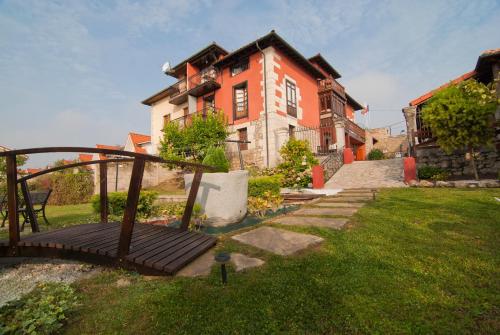 a house with a wooden bridge in front of a yard at Posada Campo in Suances