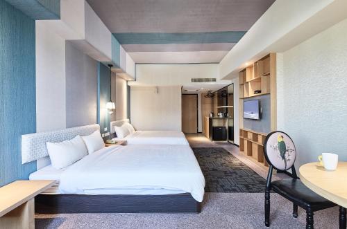 a hotel room with two beds and a desk at Kenting City Gate Hotel in Hengchun
