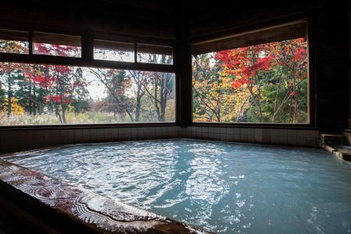 a large pool of water in a room with two windows at Takamiya Hotel Hammond in Zaō Onsen