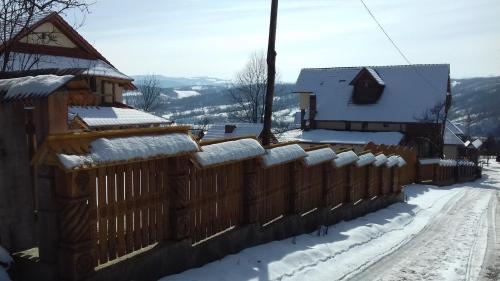 a fence covered in snow next to a house at Pensiunea Valea Branzei in Năneşti