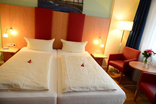 a hotel room with two beds and a red chair at Hotel National Düsseldorf (Superior) in Düsseldorf