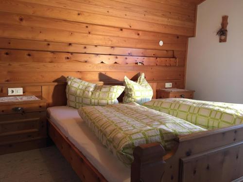 a bedroom with a bed with a wooden wall at Appartementhaus zur Loipe in Sankt Jakob in Defereggen