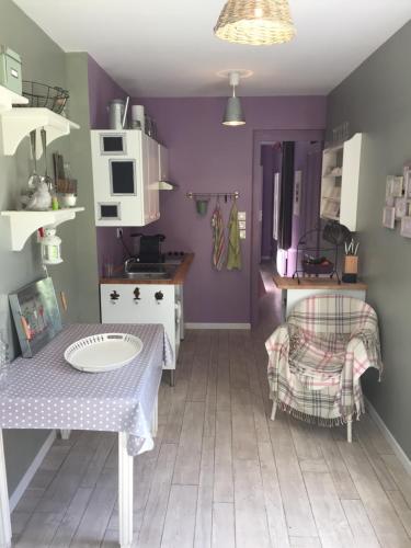 une cuisine aux murs violets et une table avec une chaise dans l'établissement Gîte de la Tour, à Saint-Aubin-sur-Mer