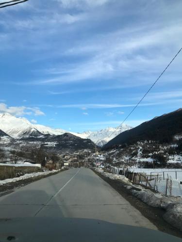 an empty road with snowy mountains in the background at Boutique hotel mestia in Mestia
