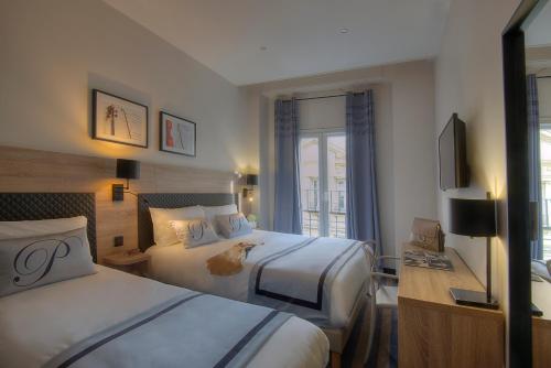 a hotel room with two beds and a television at Hotel Paganini in Nice