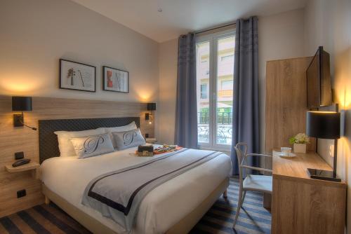ニースにあるホテル パガニーニの大きなベッドと窓が備わるホテルルームです。