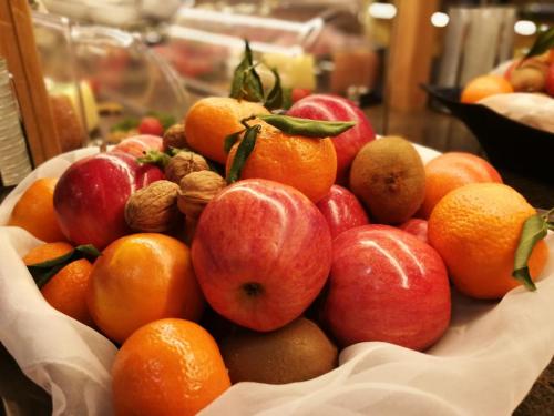 a bowl of apples oranges and other fruits on a table at Wellness Hotel Gran Risa***S in La Villa