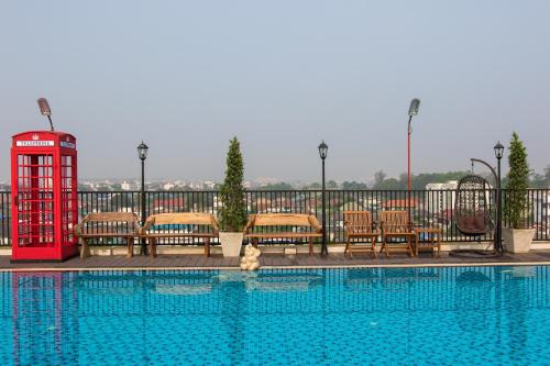 a pool with chairs and a red phone booth next to it at B-your home Hotel Don Mueang Airport Bangkok 如你家酒店 in Bangkok