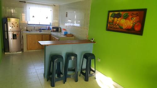 a kitchen with green walls and a counter with stools at Miss Leila in San Andrés