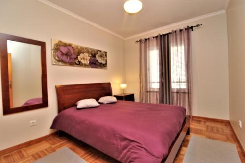 um quarto com uma cama roxa, um espelho e uma janela em Apartamento Orquidea no Funchal