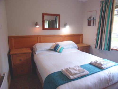 a bedroom with a bed with two towels on it at Manor House Marine & Cottages in Irvinestown