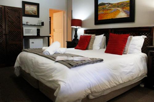 um quarto com uma grande cama branca com almofadas vermelhas em Amani Guest Lodge em Port Elizabeth