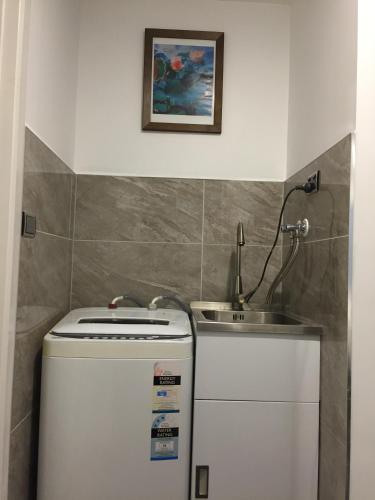 a small bathroom with a sink and a water heater at Amber Homes in Auckland