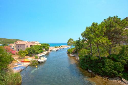 a river with boats in the water and trees at Hotel Macchia e Mare in Pietracorbara