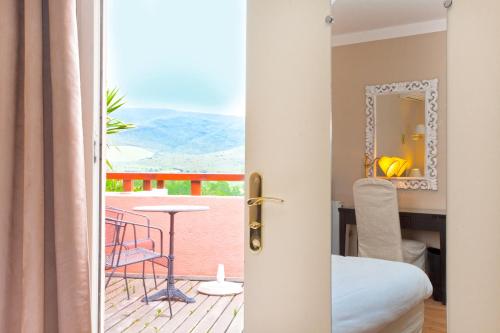 a door leading to a balcony with a table and chairs at Hotel Macchia e Mare in Pietracorbara